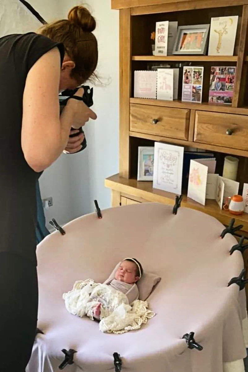 Newborn photographer capturing a tender moment as they photograph a precious newborn baby in the comfort of the client's home.